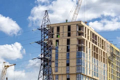 Construction Workers Build a New Apartment Building Near Power Lines Under .. Foto stock