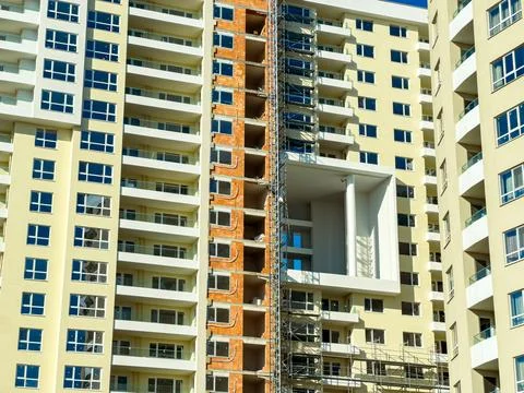 Construction workers build a new apartment building with scaffolding in the.. Stock Photos