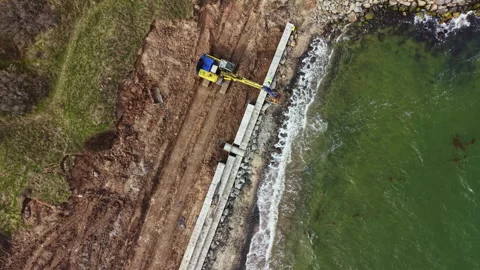 Construction workers build a sea wall along the coast to protect the land from Video stock 336516020