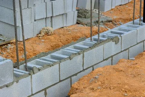 Construction workers build sturdy base with concrete blocks at building site Foto stock