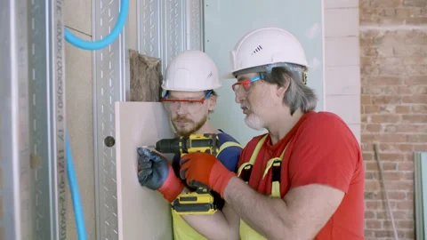 Construction workers build wall using screwdriver indoors Stock Footage 133634546