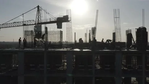 Construction workers (builders) silhouettes are on the rooftop of a building Stock Footage 145691609