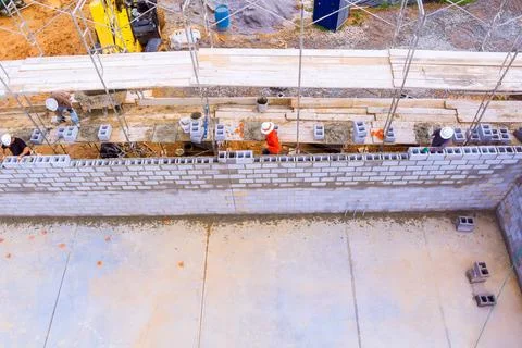 Construction workers building concrete block wall at construction site during Fotos de archivo