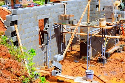 Construction workers building concrete block wall at construction site on works Stockfoto's