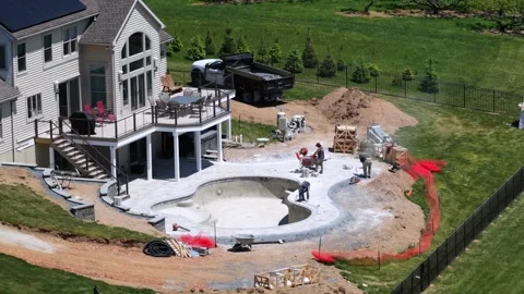 Construction workers building freeform luxury pool beside two-story home with Stock Footage 336460557