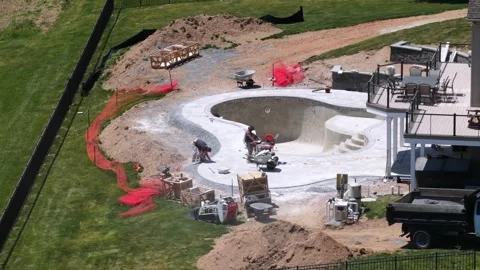 Construction workers building luxury pool with curved concrete shell in Stock Footage 336403109