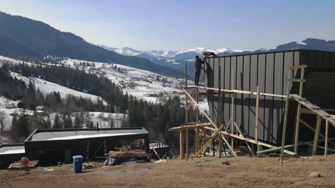 Construction workers building a modern house, winter mountain landscape with Stock Footage 303933913