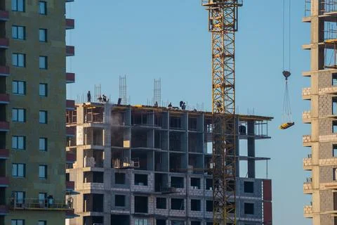 Construction workers building new apartment building using crane and equipment Stock Photos