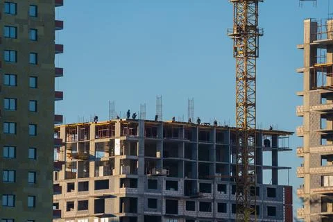 Construction workers building new apartment residential building using crane Stock Photos