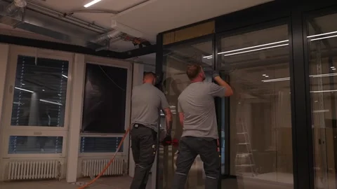 Construction workers carefully position and install a large glass partition Stock Footage 331305141