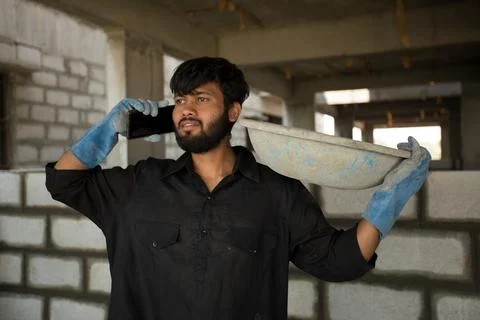 Construction workers carry cement in plastic bowls on their shoulders. Stock Photos