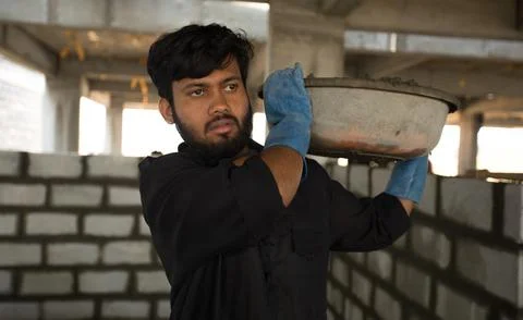 Construction workers carrying cement in plastic bowls on their shoulders. Stock Photos