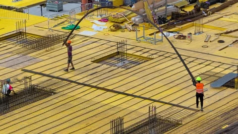 Construction workers carrying a long steel rebar at a construction site in Brno Stock Footage 341768039