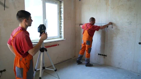 Construction workers check length with measure tape and laser tool Vidéo 100984201