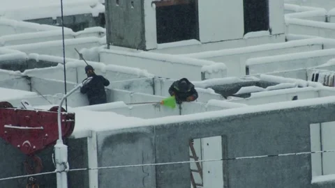 Construction workers clear snow from building under construction during winter Stock Footage 344864621