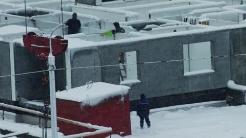 Construction workers clearing snow from building foundation on cold winter day; Stock-Footage 339866053