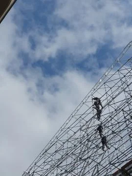 Construction workers climbing scaffolding under the sky Stock Photos