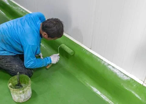 Construction workers coating green epoxy resin on edge wall. Stock-Fotos