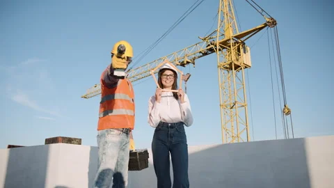 Construction workers collaborate on building site while wearing safety gear 動画素材 303228648