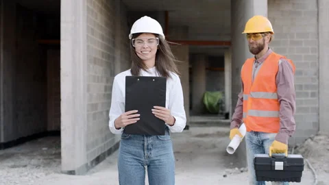 Construction workers collaborate on project plans at a building site using tools Stock-Footage 295956067