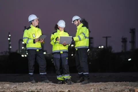 Construction workers collaborating on project analysis industrial site digi.. Stock Photos