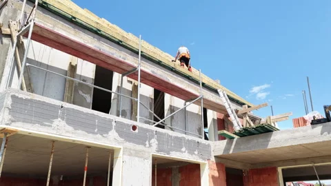 Construction Workers Complete Roofing Tasks on New Building Under Clear Sky Stock Footage 314513011