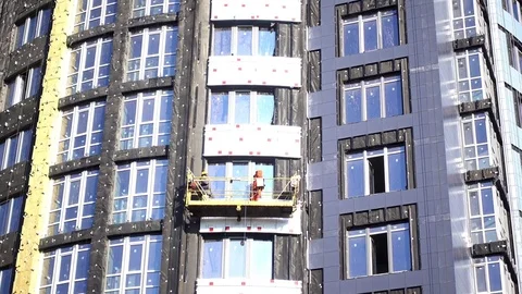 Construction workers in a cradle on the facade of a building under construction. Stock Footage 82596820