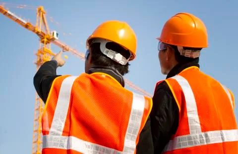 Construction workers with crane in background Foto stock
