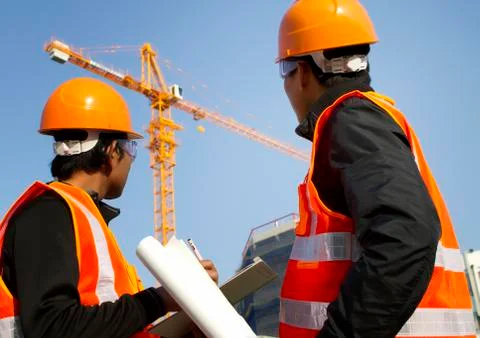 Construction workers with crane in background Stock Photos