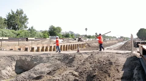Construction workers crossing foot bridge over irrigation ditch Stock Footage 11811011