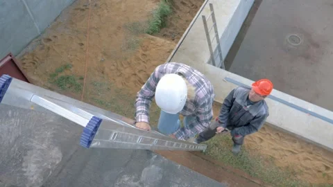 Construction workers descend a metal ladder to insure each other Stock Footage 315465847