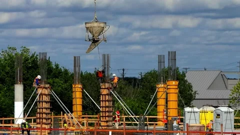 Construction workers direct concrete bucket and pour concrete into column 動画素材 153926824