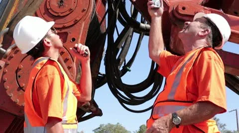 Construction workers discuss hydraulics on heavy machinery Stock Footage