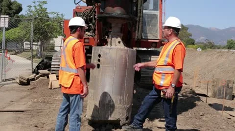 Construction workers discuss placement of heavy drill Stock Footage 11808983