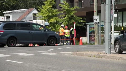 Construction workers dressed in orange with x on their shirts tops with a police Stock Footage 248715142