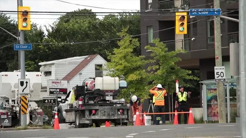 Construction workers dressed in orange with x on their shirts tops with a police Stock Footage 248715248