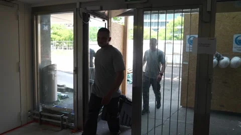 Construction workers enter a commercial building carrying ladders and Stock Footage 331304592