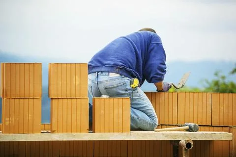 Construction workers erecting a brick shell. Illegal labour and botched work on Stockfoto's