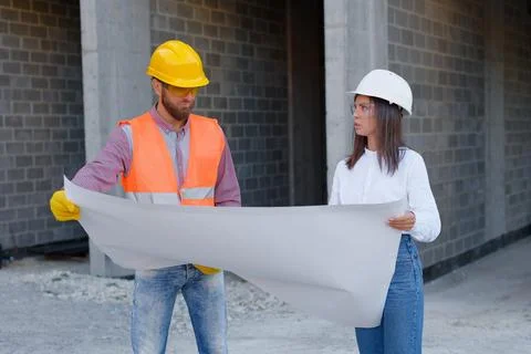 Construction workers examining blueprint on site Stock Photos