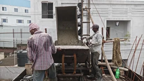 Construction workers filling slab trolley with concrete mixture and pulling at Stock Footage 317368705