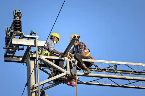 Construction workers fixing overhead electrical cables of Pune Metro project. Stock Photos