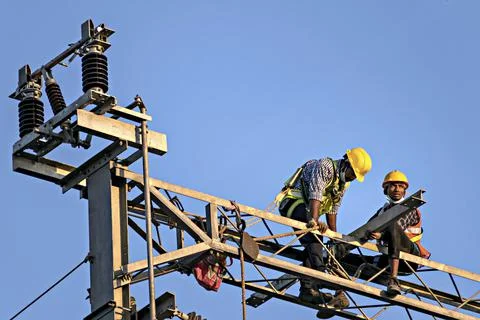 Construction workers fixing overhead electrical cables of Pune Metro project. Stock Photos
