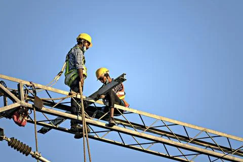 Construction workers fixing overhead electrical cables of Pune Metro project. Stock Photos