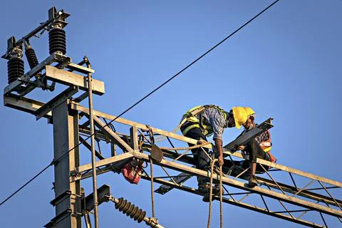 Construction workers fixing overhead electrical cables of Pune Metro project. Stock Photos
