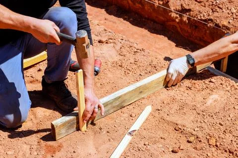 Construction workers framing foundation for new building during daylight on Stock Photos