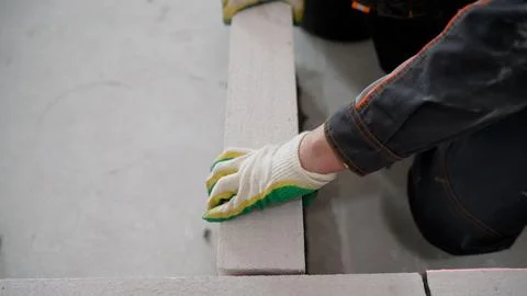 A construction worker's gloved hand laying an autoclaved aerated concrete b.. Фото