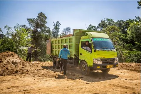 Construction workers with a green tipper truck clearing soil in Bali, Indonesia Stock Photos