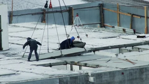 Construction workers guide accurate placement of heavy concrete slab hoisted by Stock Footage 347580651