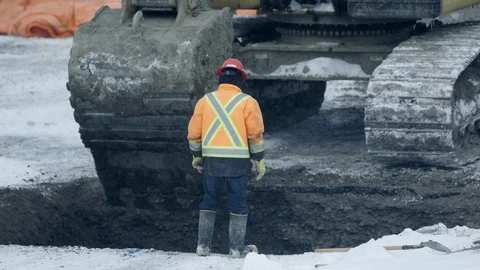 Construction workers guide excavator bucket digging hole in winter constructi Stock Footage 125889697