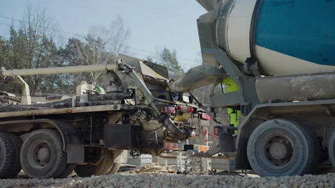 Construction workers guiding concrete mixer truck, transferring cement through Stock Footage 306395737